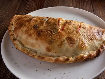 Calzone tout juste sortie du four, à l'origan, sur assiette blanche
